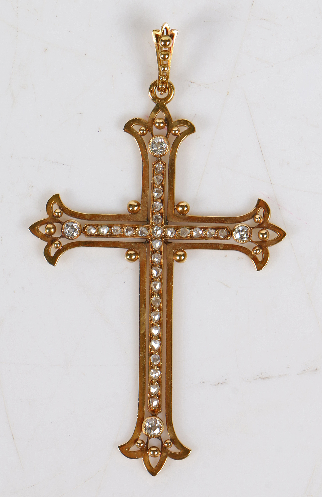 A French gold and diamond mounted cross pendant, the beaded bail above a diamond set cross with