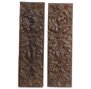 A pair of 18th Century carved oak panels, decorated with cherubs and putti amongst foliate