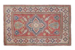 A Caucasian style rug, made in Pakistan, having a red and cream ground set with a central hooked gul