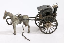 A folk art horse and hansom cab, the dappled grey painted horse pulling the black cab, 24cm wide (