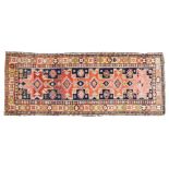 A Caucasian runner rug, Dagehstan, having a blue red and yellow ground set with five main guls and