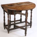 A Charles II oak drop leaf table, the circular top above turned supports united by stretchers,