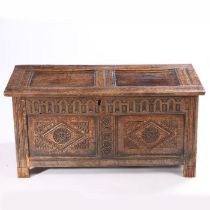 A 17th Century oak coffer, with a twin panel hinged top above a thumb craved frieze and two