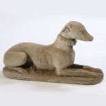 A composite greyhound statue, reclining position on a plinth, 66cm long, 38cm high