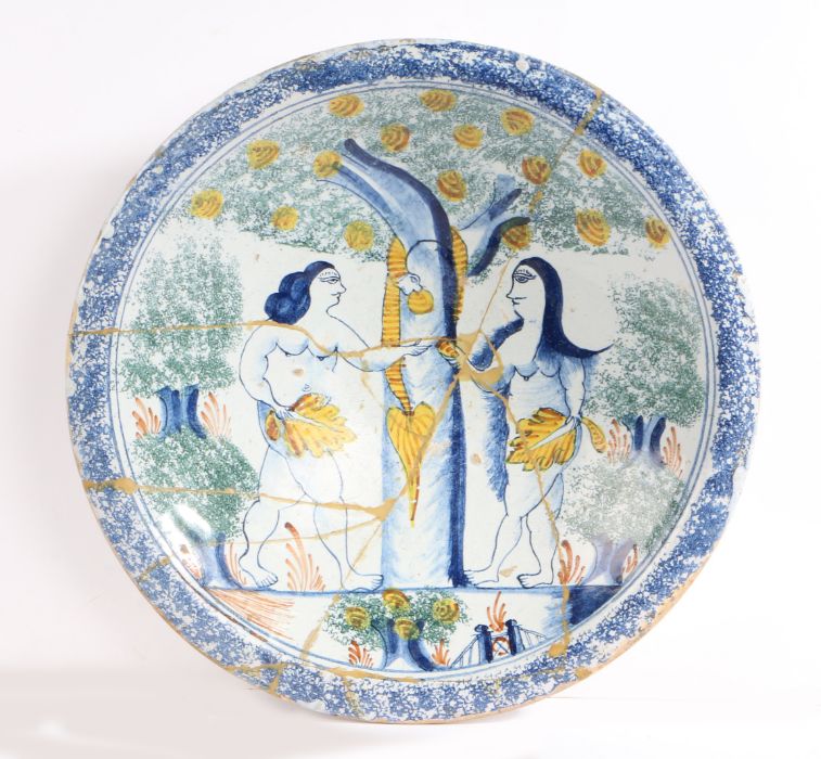 An 18th Century "Adam and Eve" delft charger, the central field decorated with Adam and Eve