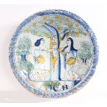 An 18th Century "Adam and Eve" delft charger, the central field decorated with Adam and Eve