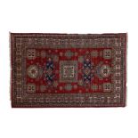 A Caucasian Kazak rug, having a red ground set with a central hooked gul together with memling