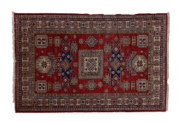 A Caucasian Kazak rug, having a red ground set with a central hooked gul together with memling