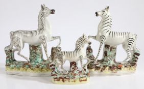 A near pair of 19th Century Staffordshire zebras, 26cm high, together with a smaller Staffordshire