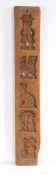 A treen biscuit mould, carved with a seated cat, bird and figures, 53.5cm high, 9cm wide