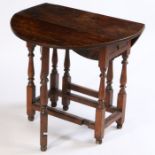 A small Charles II and later oak drop leaf table, the circular drop flap top above a single drawer