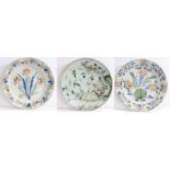 Three 18th Century polychrome delft chargers, the first decorated with a bird amongst foliage,
