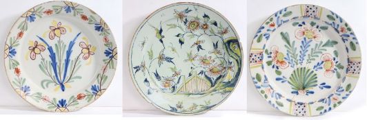 Three 18th Century polychrome delft chargers, the first decorated with a bird amongst foliage,