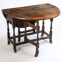 An 18th Century oak drop leaf table, the circular drop flap top above turned supports and fluted