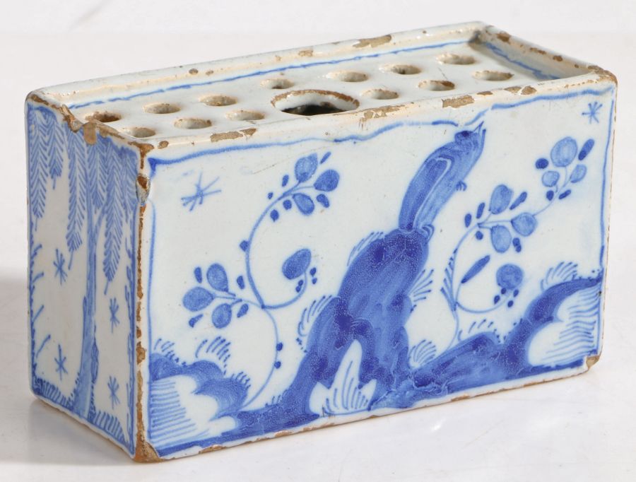 An 18th Century Delft flower brick, with foliate decorated front and back flanked by willow tree