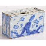 An 18th Century Delft flower brick, with foliate decorated front and back flanked by willow tree
