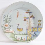 An 18th Century Bristol delft charger, decorated with a crane surrounded by foliage and a zig-zag