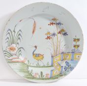 An 18th Century Bristol delft charger, decorated with a crane surrounded by foliage and a zig-zag