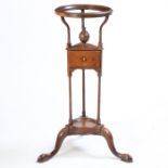 A George III mahogany washstand, the circular top above a slender supports and a small drawer