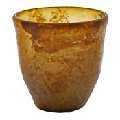 A Roman amber glass beaker, 3rd - 4th Century AD, of tapering form with a section of the rim