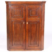 A GEORGE III OAK HANGING BARREL BACK CORNER CUPBOARD.