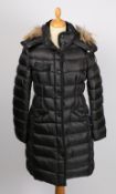 A knee length Moncler black down coat with fur collar, size 34.