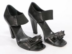 A pair of Prada leather open toe heels with elastic ankle strap and leather bow detail. Size 35