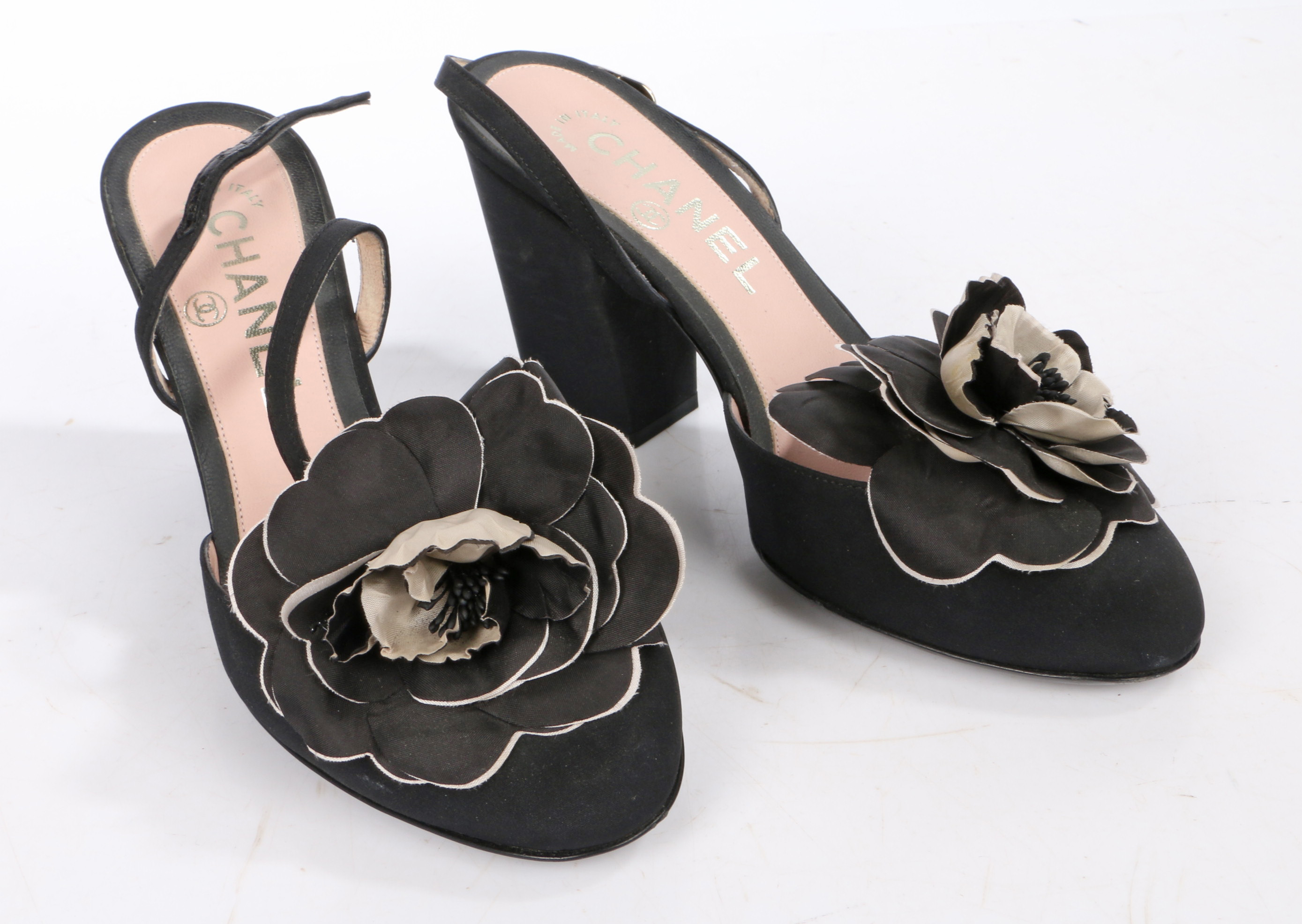 A pair of Chanel black suede open toed heels with block heel and camellia decoration to the toe.