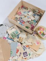 A collection of used loose world stamps, housed in a small box and envelope