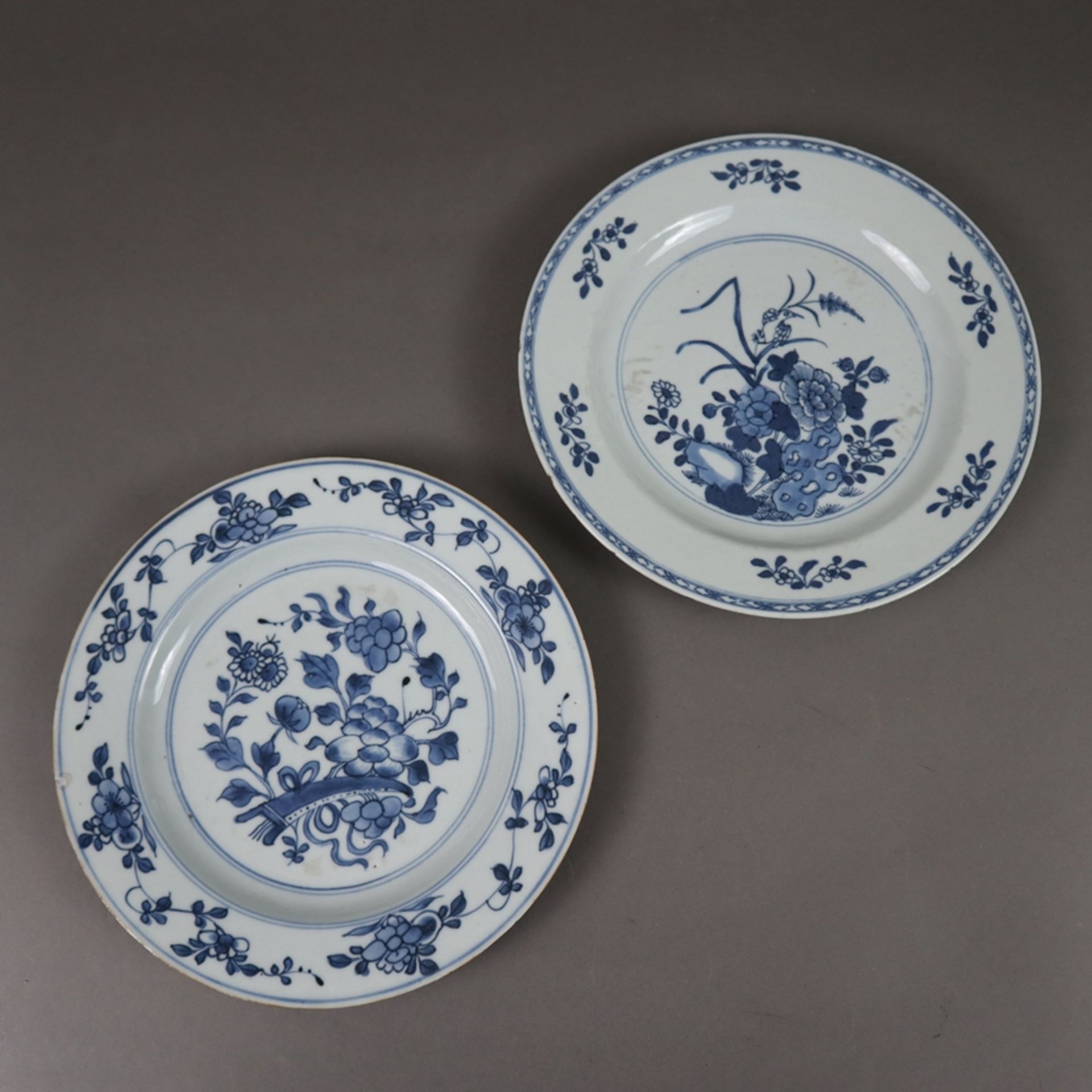 Zwei Teller - China, beide mit floralem Dekor in Unterglasurblau, nicht identisch, Glasurbestoßunge