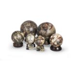 A assembled set of six variegated rouge and grey and black marble spheres on stands probably ear...