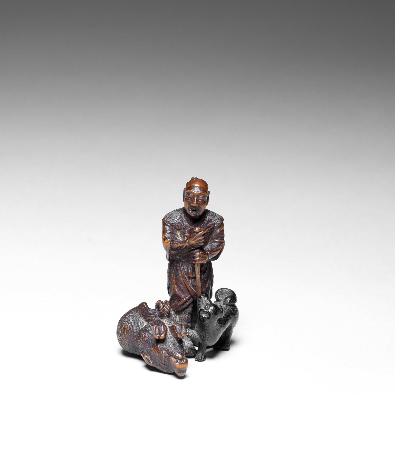 NETSUKE EN BOIS ET EN &#201;B&#200;NE REPR&#201;SENTANT UN CHASSEUR AVEC SON CHIEN ET UN SANGLIE...