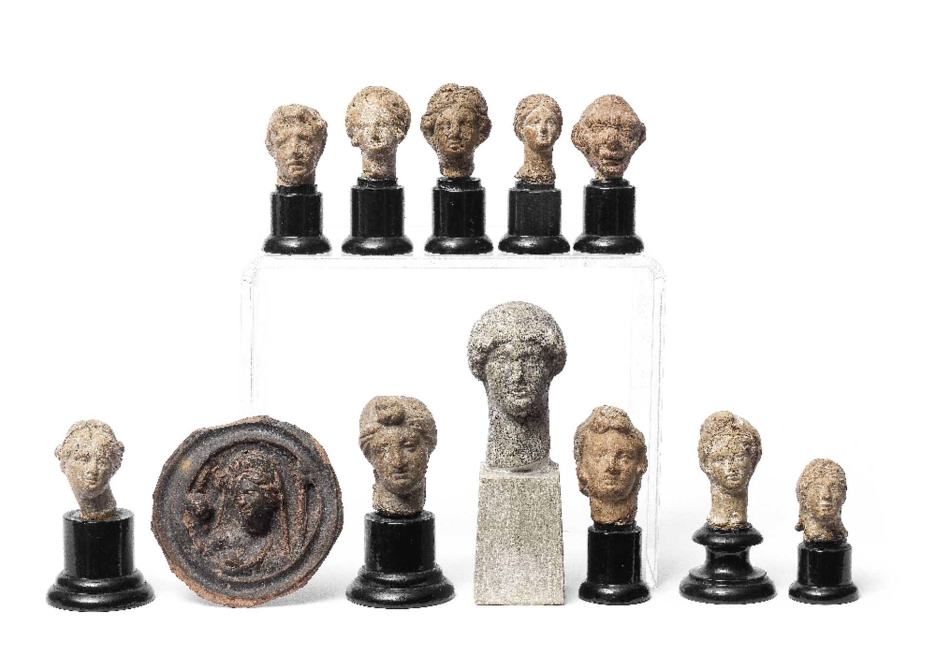 Eleven Greek and Roman terracotta heads and a black-glazed roundel 12