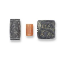 A Persian black stone cylinder seal, an Old Babylonian carnelian cylinder seal and a Syrian blac...