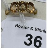 10ct yellow gold ladies ring set with three brownish cut stones off set by white topaz shoulders. [