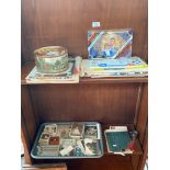 Two shelves of odds to include tray of postcards and photos, Sealed Kunzle Dundee Cake, Royalty