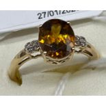 10ct yellow gold ladies ring set with an Orange cut glass stone off set by diamond shoulders. [