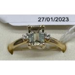 10ct yellow gold ladies ring set with a pale green emerald cut spinel stone off set with two