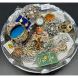 Dish containing a quantity of costume jewellery items, brooches, cliosonne egg and Timberland watch.
