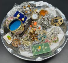 Dish containing a quantity of costume jewellery items, brooches, cliosonne egg and Timberland watch.
