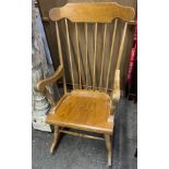 Light wood rocking chair with arm rests.