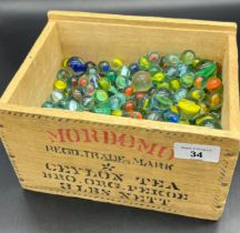 A Vintage Mordomo tea advertising wooden box containing a large quantity of cat eye marbles.