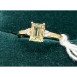 10ct yellow gold ladies ring set with a pale green spinel stone off set by white quartz stones. [