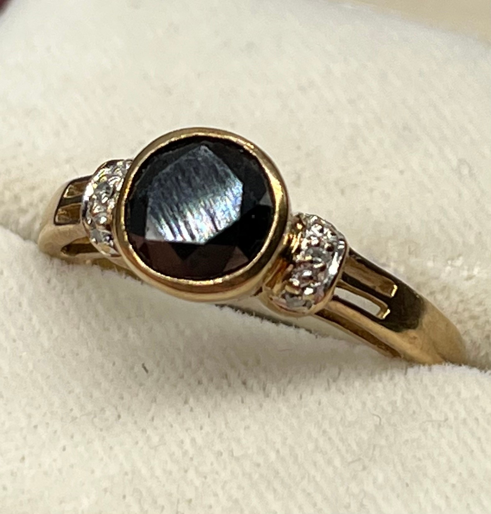 A 9ct yellow gold ring set with a 1.44ct black diamond stone off set by smaller white diamonds- 0.