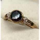 A 9ct yellow gold ring set with a 1.44ct black diamond stone off set by smaller white diamonds- 0.