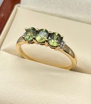 10ct yellow gold ladies ring set with three green stones off set by clear stone shoulders. [Ring