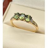 10ct yellow gold ladies ring set with three green stones off set by clear stone shoulders. [Ring