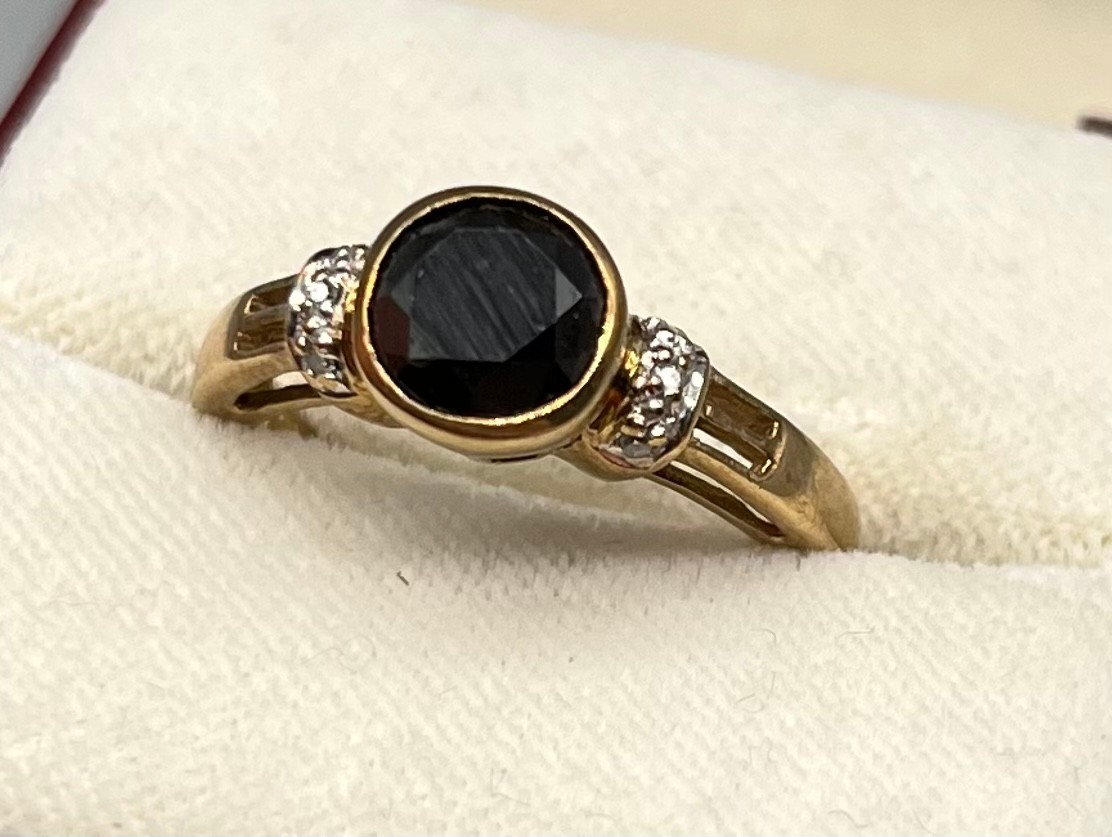 A 9ct yellow gold ring set with a 1.44ct black diamond stone off set by smaller white diamonds- 0. - Image 2 of 4