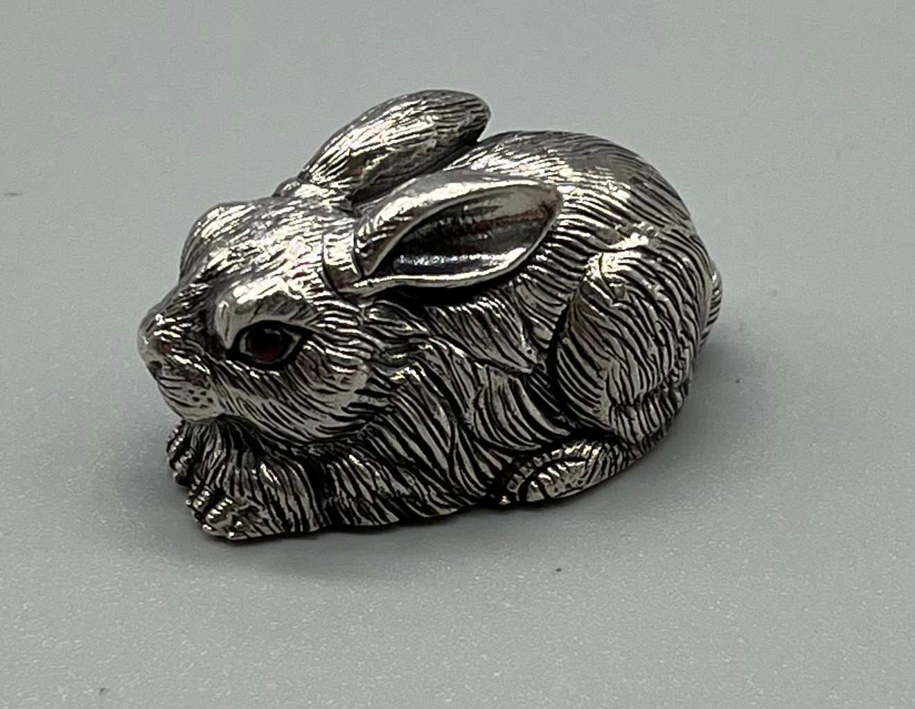 A Sterling silver sculpture of a rabbit set with ruby eyes. [3cm in length]