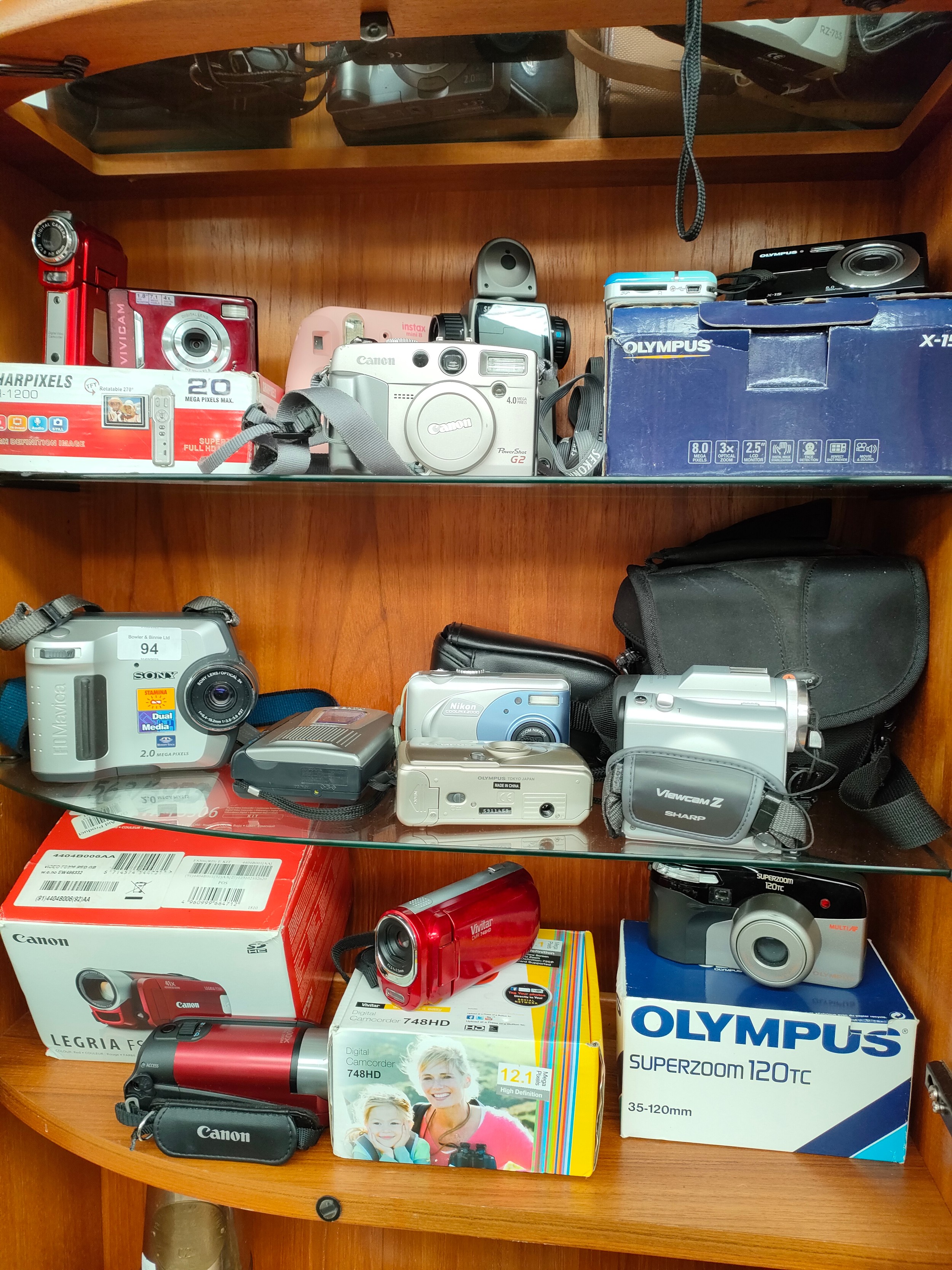 3 Shelves of cameras to include canon, Sony, canon camcorders etc